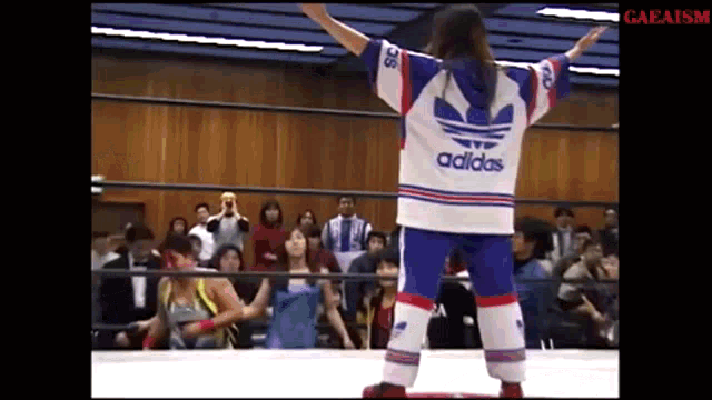 a person wearing an adidas shirt stands in a wrestling ring