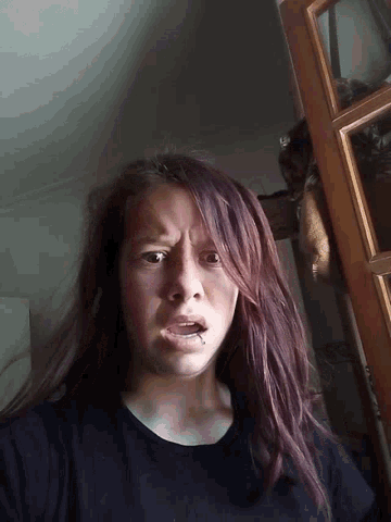 a woman with purple hair is making a funny face with her mouth open