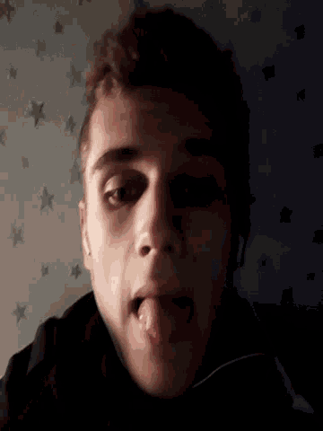 a man sticking his tongue out in front of a starry wall