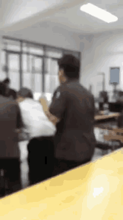 a blurry picture of a man sitting at a table in a classroom