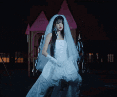 a woman in a white wedding dress is standing in front of a fire