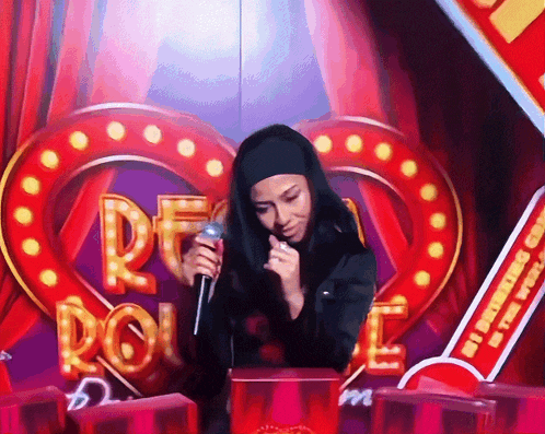 a woman is singing into a microphone in front of a sign that says peace