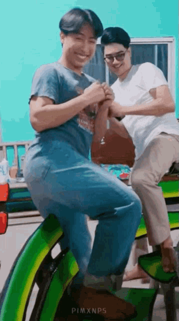 two men are sitting on a green chair and laughing .