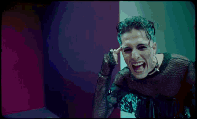 a man with green hair is screaming in a dark room .