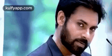 a man with a beard is looking at the camera .