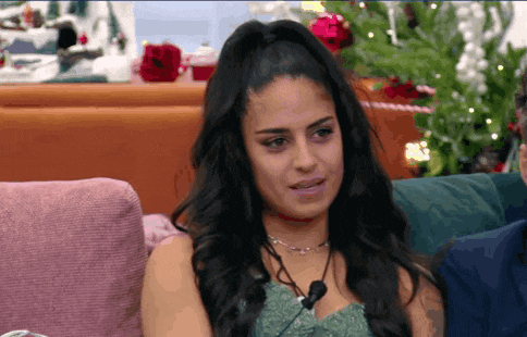 a woman is sitting on a couch with a christmas tree in the background .