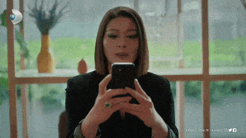 a woman is looking at her phone with the words kanali.com.tr on the bottom right