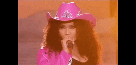 the woman is wearing a pink cowboy hat and holding a microphone .