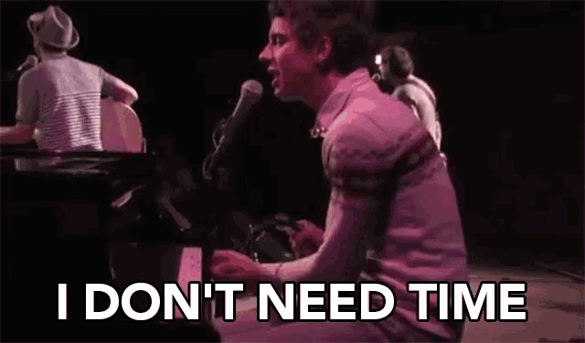 a man singing into a microphone while playing a piano with the words i don t need time below him