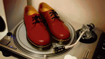 a pair of red shoes are sitting on top of a record player