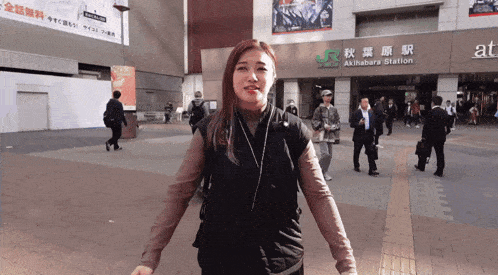 a woman is walking in front of a building that says akihabara station