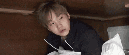 a young man is laying on a bed with his eyes closed while holding a piece of paper .