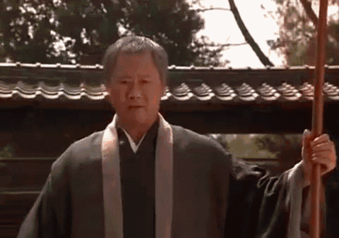 a man in a kimono is holding a cane in front of a roof .