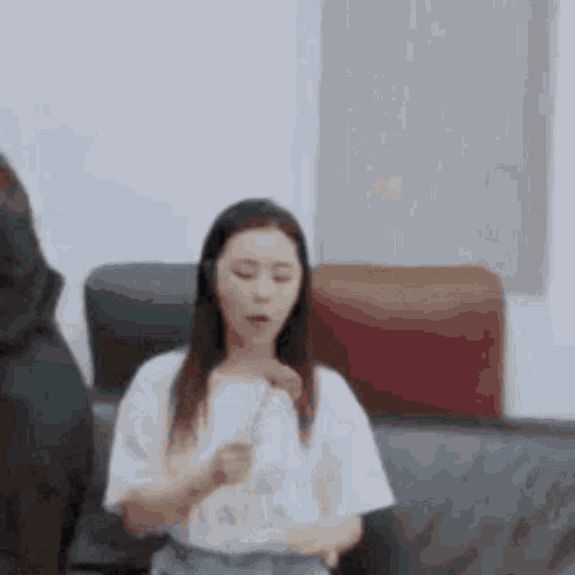 a woman is sitting on a couch eating a piece of pizza .