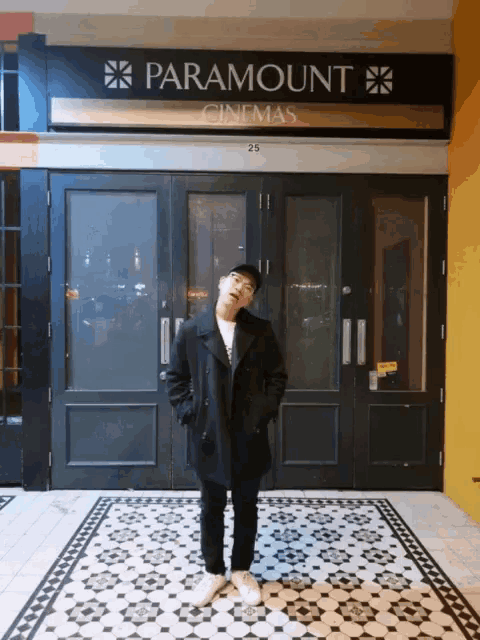 a man is standing in front of a paramount cinema