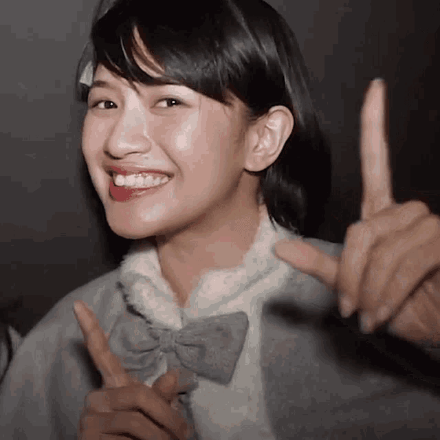 a woman with a bow on her jacket is smiling and pointing