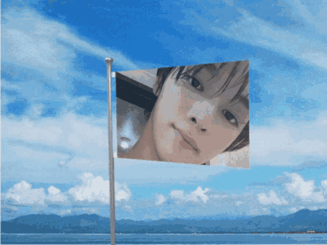 a flag with a picture of a woman on it against a blue sky