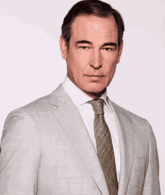 a man is wearing a suit and tie and looking at the camera