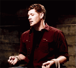 a man in a maroon shirt is tied up with rope