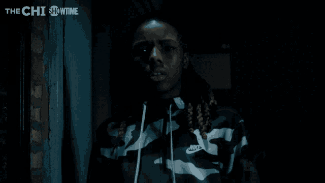 a man in a nike jacket stands in the dark