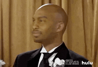 a man in a tuxedo and tie is looking at something .
