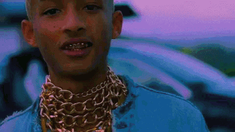 a close up of a man wearing a denim jacket and gold chains .