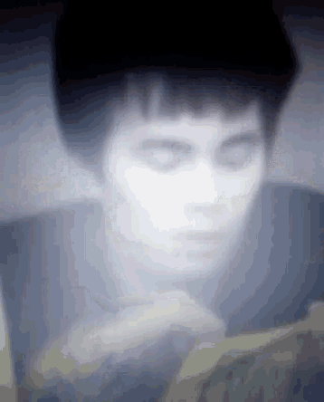 a blurry picture of a man reading a book with his eyes closed .