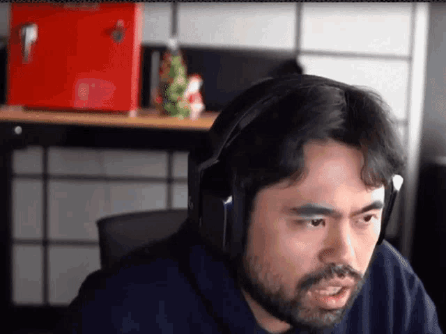 a man with a beard is wearing headphones while sitting in front of a computer .
