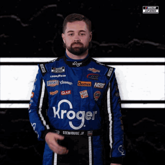 a man in a kroger sponsored race suit stands in front of a black and white background