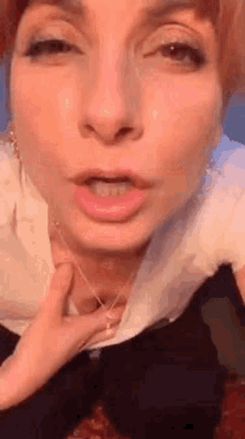 a close up of a woman 's face with her mouth open and her hand on her chest .
