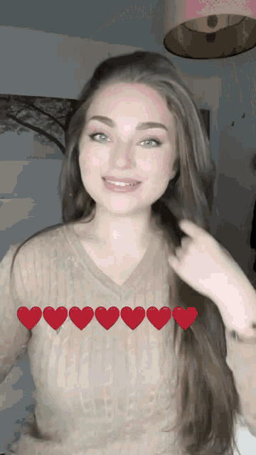 a woman wearing a tan sweater with red hearts on it