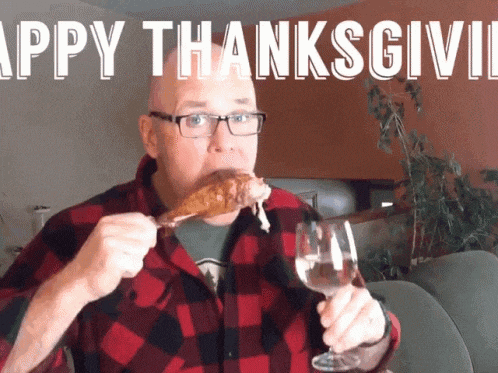 a man in a plaid shirt is eating a chicken leg and drinking a glass of wine