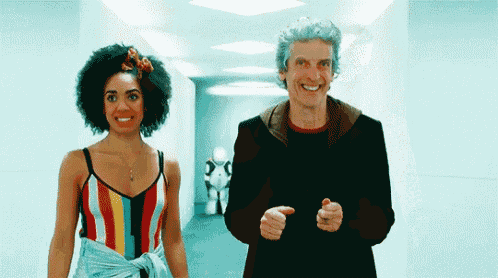 a man and a woman are walking down a hallway and smiling .