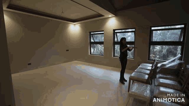 a woman stands in an empty room with the words made in animotica on the bottom right