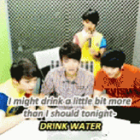 a group of young men are sitting around a table and one of them is saying " drink water "