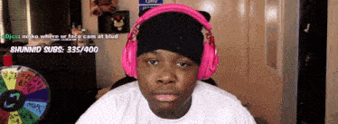 a man wearing pink headphones is sitting in front of a wheel that says 8hunmid subs 335/400
