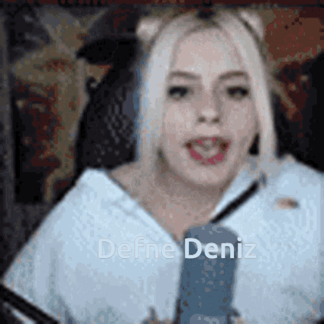 a woman is talking into a microphone and the name defne deniz is on the screen