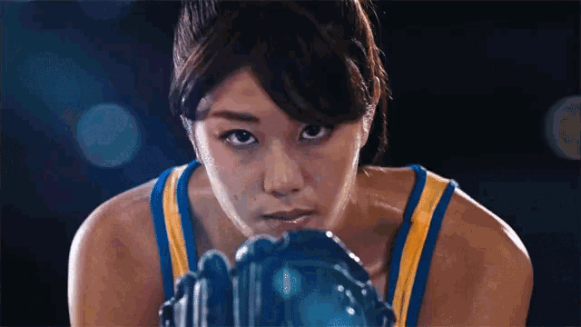 a woman in a blue and yellow tank top is wearing boxing gloves ..