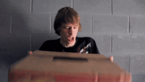 a man in a black shirt is holding a cardboard box in his hands