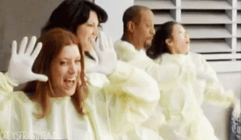 a group of people wearing yellow gowns and white gloves are standing in a room .
