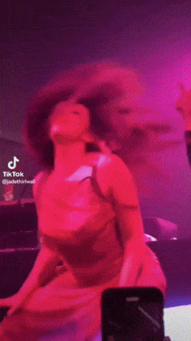 a tiktok video of a woman dancing with pink smoke coming out of her mouth