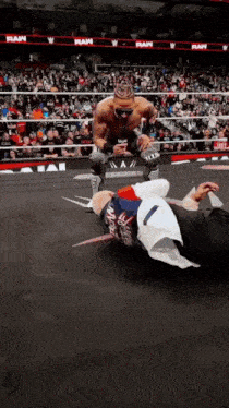 a wrestler is kneeling over another wrestler who is laying on the ground during a raw show