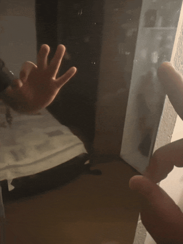 a person 's hand is reaching out towards another person 's hand in a mirror