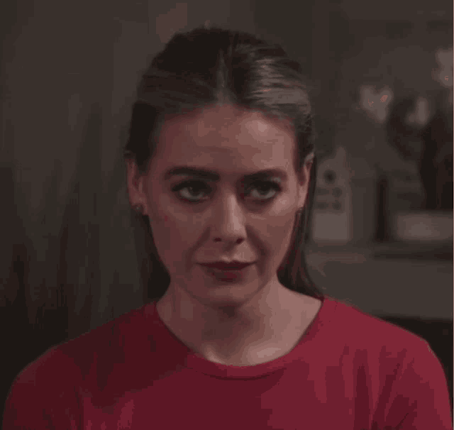 a woman wearing a red shirt is looking down at something