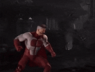 a man in a red superhero costume is standing in the dark .