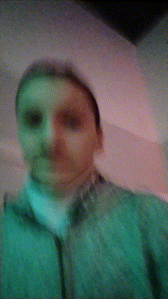 a person wearing a green jacket and a white turtleneck looks at the camera