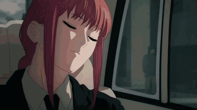 a girl with long red hair is sleeping in a car