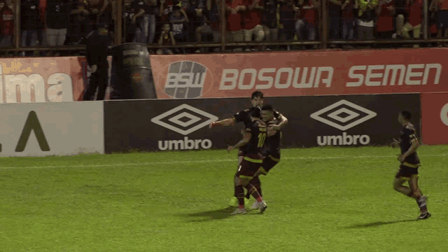 soccer players celebrate a goal in front of a bsw bosowa semen banner