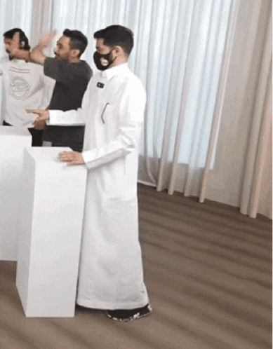 a man wearing a mask is standing in front of a white podium