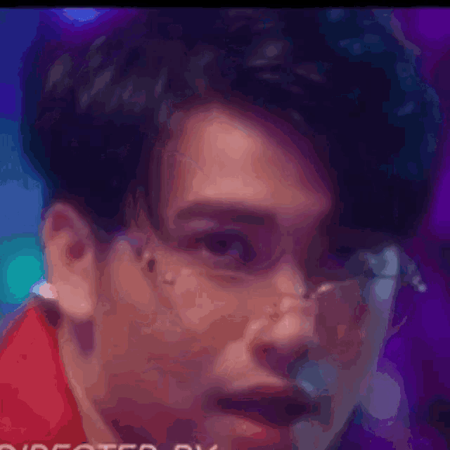 a close up of a man wearing glasses and a red shirt with a purple background
